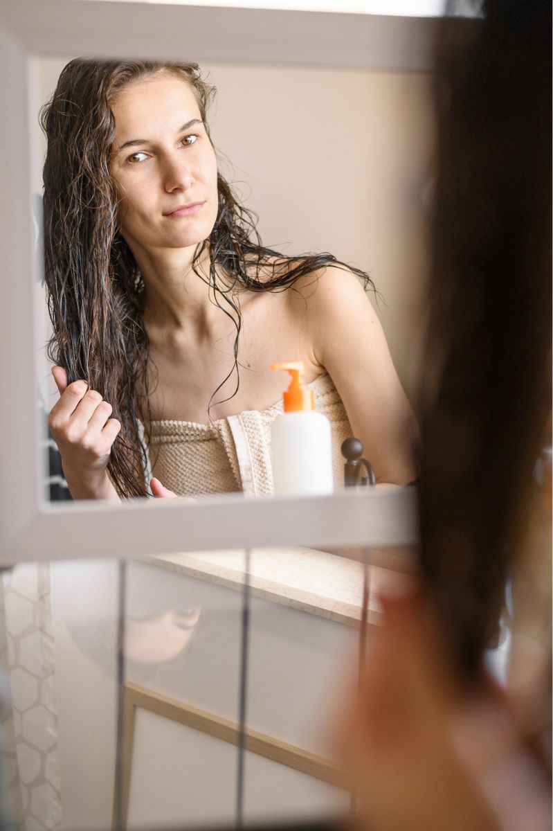 Chica colocándose crema para el pelo luego de ducharse 