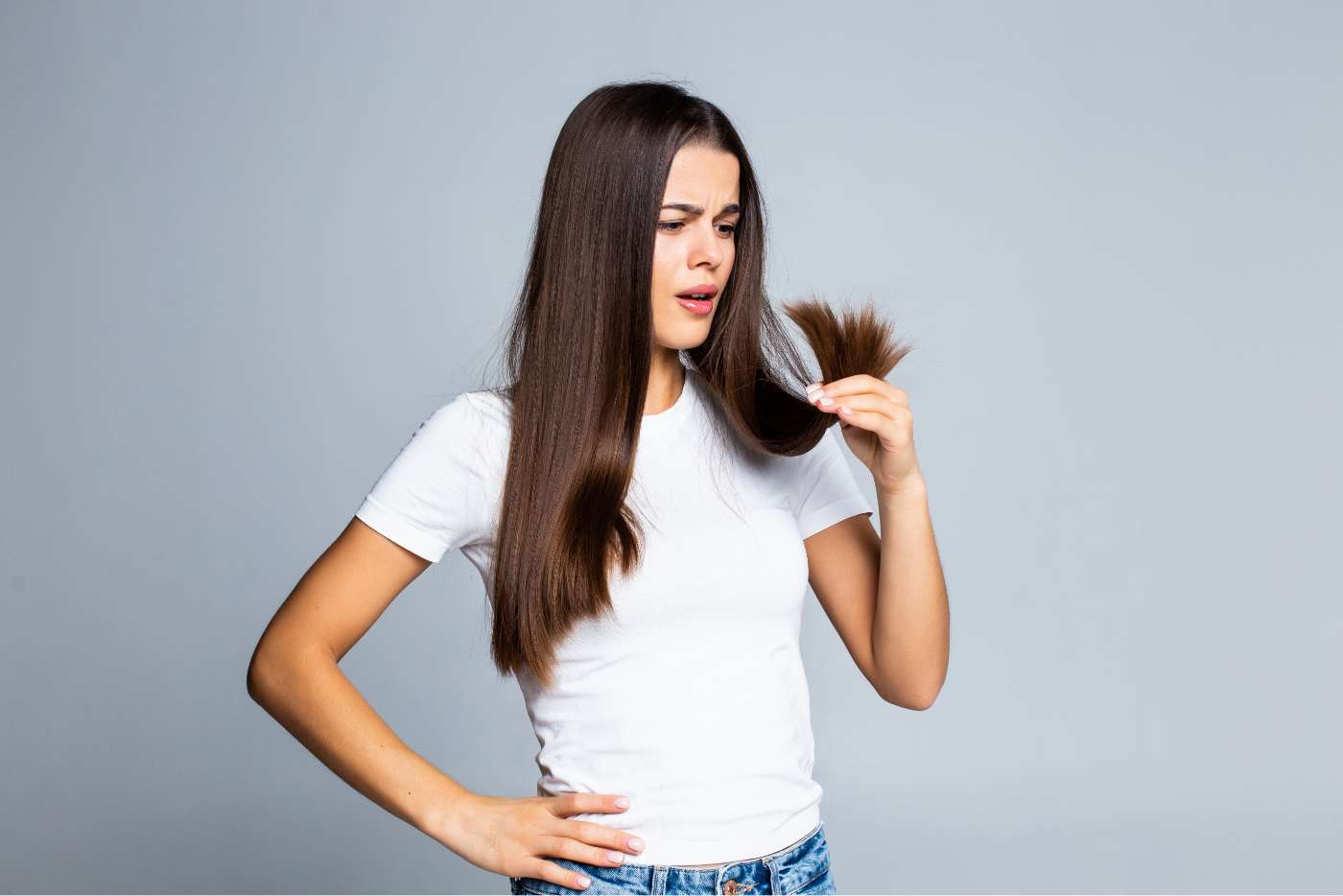 Chica mirándose las puntas abiertas de su pelo largo