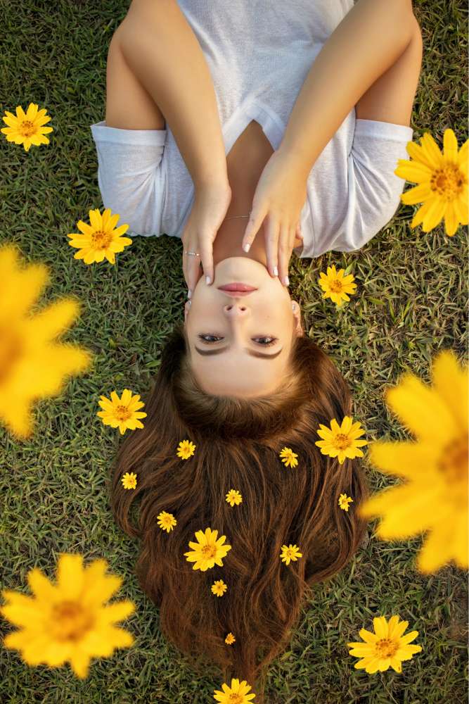 Chica tendida en el césped con hermoso cabello mientras caen flores